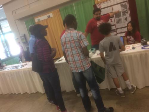 Ye group member describing poster information to a young visitor